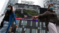 Warga melintas di depan videotron di Ibu Kota Beijing, Kamis (4/8/222) yang menampilkan peluncuran roket China ke Taiwan. (Noel Celis/Getty Images)