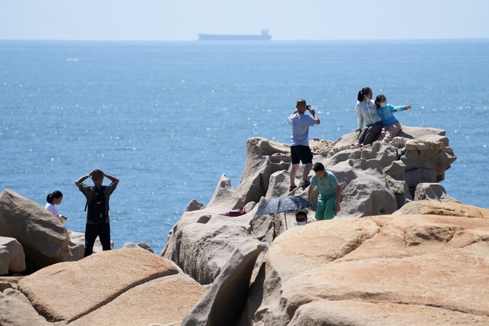Tourists pose for photos on the waterfront at the 68-nautical-mile scenic spot, the closest point in mainland China to the island of Taiwan, in Pingtan in southeastern China's Fujian Province, Friday, Aug. 5, 2022. China conducted 