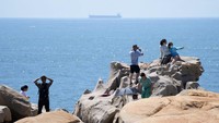 Turis mengambil foto di Pantai Pingtan, China, Jumat (5/8/2022). Pantai tersebut merupakan jarak terdekat dengan Taiwan, sekitar 68 mil laut. (AP Photo/Ng Han Guan)
