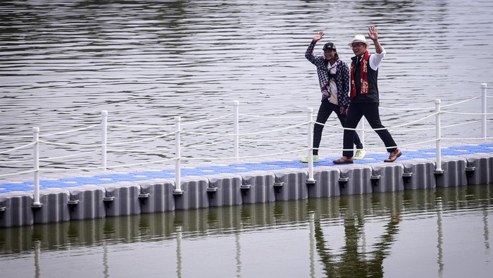 Gubernur Jawa Barat Ridwan Kamil (kanan) berjalan bersama Bonge (kiri) di atas floating brigde saat peresmian Situ Rawa Kalong di Curug, Depok, Jawa Barat, Jumat (5/8/2022). Selesainya revitalisasi Situ Rawa Kalong yang dilengkapi dengan beberapa fasilitas seperti jogging track, tembok mural dan floating brigde bertujuan menjadikan situ sebagai tempat destinasi wisata.