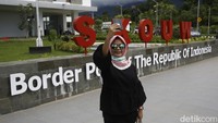 Seorang warga berfoto di Pos Lintas Batas Negara (PLBN) Skouw di Indonesia yang berbatasan langsung dengan Papua Nugini. (Muhammad Ridho/detikcom)