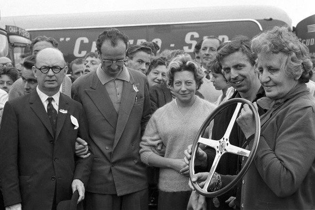 Penasaran dengan sosok asli Laura Ferrari? Di foto tertanggal 16 Juli 1960 ini, Laura berada di pojok kiri. Ia hendak memberikan tropi kepada pebalap Tony Brooks saat ajang Grand Prix of Great Britain. (Foto: GC Images/MEGA)