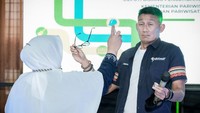Di acara yang didominasi para emak-emak itu, tiba-tiba Sandiaga disemprot oleh Ibu Suriani. Ternyata ibu itu sedang mempromosikan produknya di depan Sandiaga. (dok. Kemenparekraf)