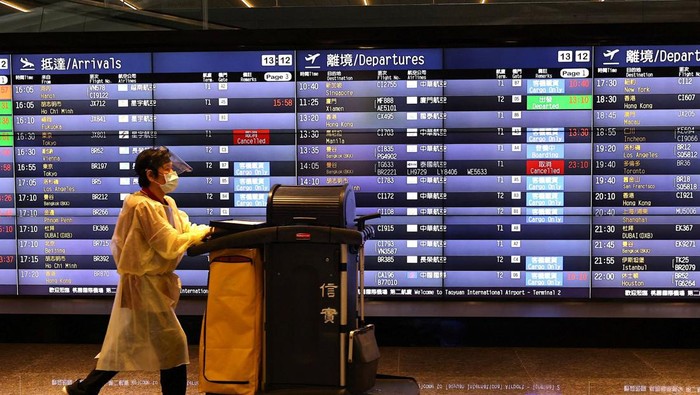 A airport staff walks past a board showing departure statuses at Taoyuan International Airport in Taoyuan City, Taiwan, August 4, 2022. REUTERS/Ann Wang