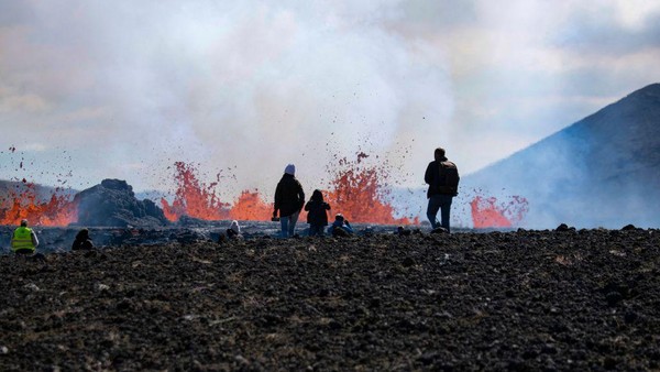 Orang-orang mengunjungi lokasi gunung berapi yang baru meletus yang terjadi di lembah Meradalir, dekat gunung Fagradalsfjall, Islandia, Kamis, (4/8/2022). (Jeremie Richard/AFP/Getty Images)