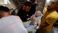 Sejumlah orang mengevakuasi seorang wanita tua yang terluka dan masih shok akibat ledakan dari rudal Israel. (Mohammed Salem/Reuters)