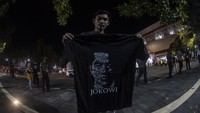 Seorang warga yang mendapat kaos dari Jokowi pamer di depan kamera.