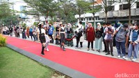 Layaknya peraga busana profesional, para peserta itu melenggang di atas catwalk panjang disaksikan warga lainnya dan aksi para fotografer mengabadikan momen. (Foto: Esti Widiyana/detikJatim)