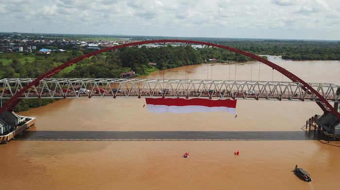 Foto udara sebuah bendera merah putih dibentangkan di Jembatan Kahayan, Palangka Raya, Kalimantan Tengah, Sabtu (6/8/2022). Aksi pembentangan bendera merah putih sepanjang 40 x 8 meter tersebut diikuti oleh TNI, Polri, Basarnas, BPBD, dan relawan ERP yang bertujuan untuk menumbuhkan rasa jiwa nasionalisme kepada generasi muda serta menyemarakkan HUT ke-77 Kemerdekaan Republik Indonesia. ANTARA FOTO/Makna Zaezar/nz