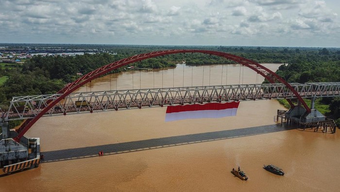 Foto udara sebuah bendera merah putih dibentangkan di Jembatan Kahayan, Palangka Raya, Kalimantan Tengah, Sabtu (6/8/2022). Aksi pembentangan bendera merah putih sepanjang 40 x 8 meter tersebut diikuti oleh TNI, Polri, Basarnas, BPBD, dan relawan ERP yang bertujuan untuk menumbuhkan rasa jiwa nasionalisme kepada generasi muda serta menyemarakkan HUT ke-77 Kemerdekaan Republik Indonesia. ANTARA FOTO/Makna Zaezar/nz