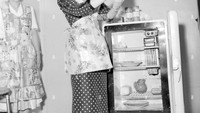 Terlihat seorang ibu sedang mengambil persediaan susu dari kulkas mini. Tidak terlalu banyak makanan tersedia, tetapi ada beberapa tempat yang mungkin terdapat makanan di dalamnya. Foto: alamy.com