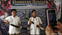 Dua orang anak berfoto dengan artefak yang dipamerkan.
