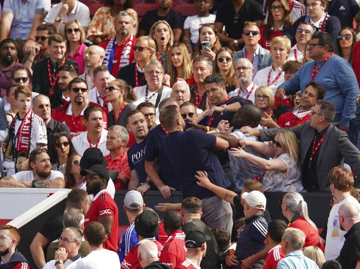 Fans fight on the tribune during the English Premier League soccer match between Manchester United and Brighton at Old Trafford stadium in Manchester, England, Sunday, Aug. 7, 2022. (AP Photo/Dave Thompson)