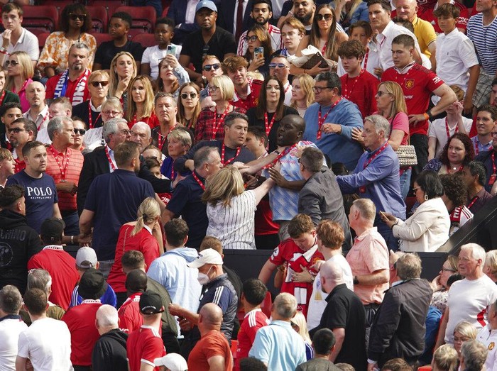 Fans fight on the tribune during the English Premier League soccer match between Manchester United and Brighton at Old Trafford stadium in Manchester, England, Sunday, Aug. 7, 2022. (AP Photo/Dave Thompson)