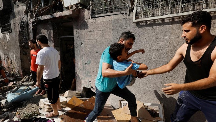 Palestinians evacuate a boy following an Israeli air strike on a house, amid Israel-Gaza fighting, in the northern Gaza Strip August 7, 2022. REUTERS/Mohammed Salem