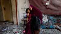 Seorang wanita Palestina dan putrinya yang menangis setelah rumah mereka terkena serangan Israel.