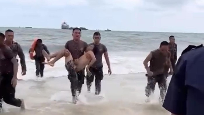Polisi saat mengevakuasi dua bocah yang terseret ombak di Pantai Balikpapan.