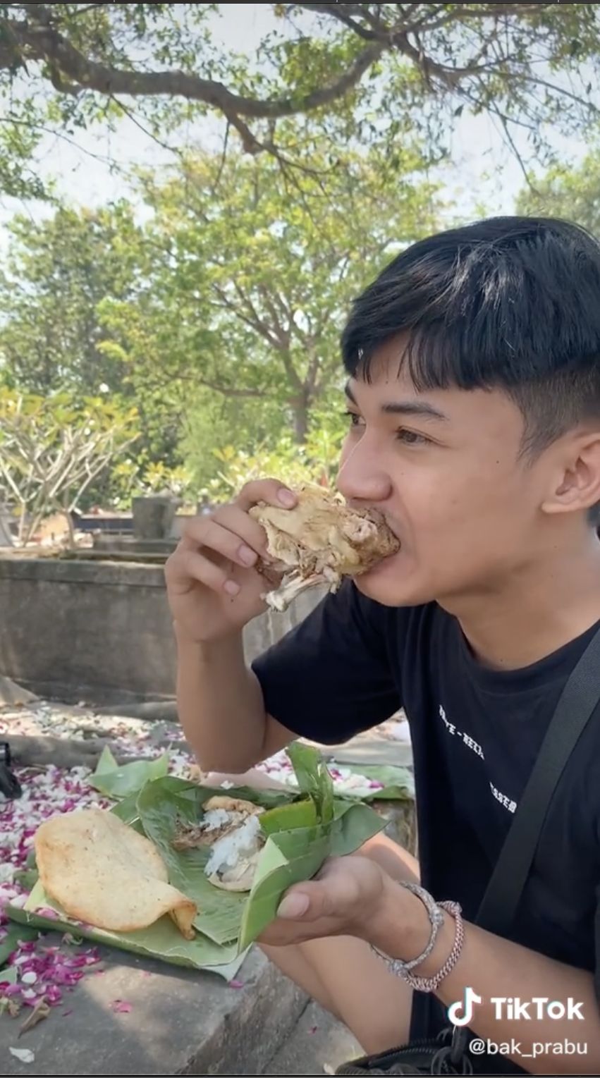 Pria coba makan sesajen berisi nasi ayam di kuburuan. Ternyata rasanya masih enak!
