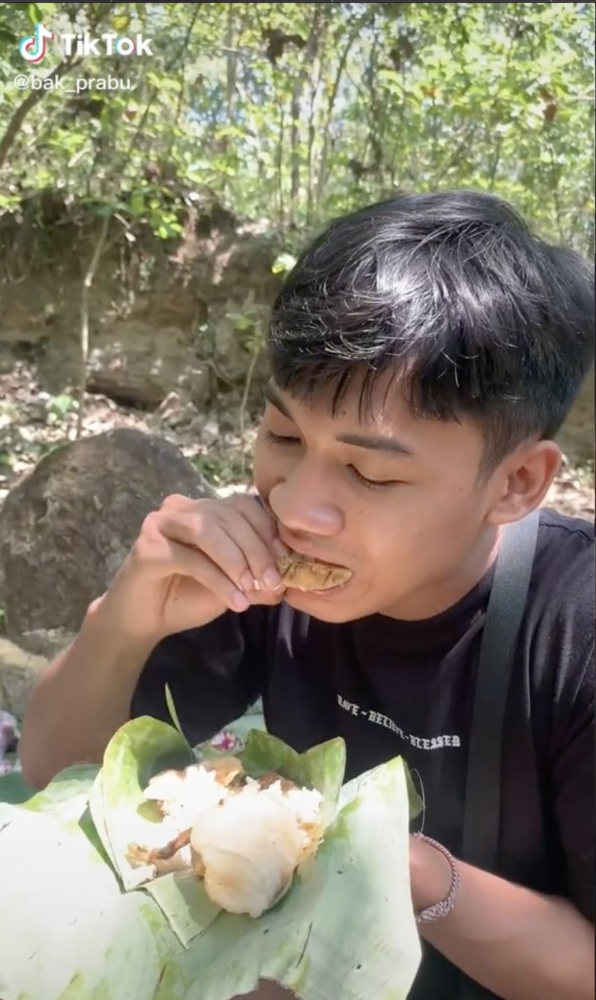 Pria coba makan sesajen berisi nasi ayam di kuburuan. Ternyata rasanya masih enak!