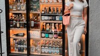 Jalan-jalan ke mall, ini gaya Riesca Rose saat berpose di depam gerai wine. Banyak berjejer botol wine dengan berbagai merek di sana. Foto: Instagram @riesca_rose
