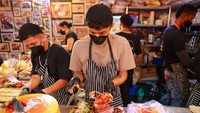 Seorang chef menyiapkan pesanan sandwich sambil bergaya baguette.