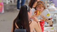 Seorang pengunjung menyantap sandwich yang dibelinya di festival tersebut. Terlihat ekspresinya yang begitu menikmati makanan tersebut.