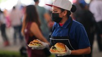 Seorang pelayan membawakan sandwich ke salah satu pengunjung festival tersebut.