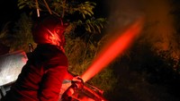 Petugas pemadam kebakaran memadamkan api yang membakar lahan di Desa Simulop, Pangururan, Samosir, Sumatera Utara, Minggu (7/8/2022) malam.