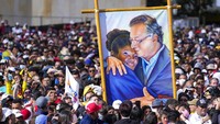 Pendukung Presiden Kolombia Gustavo Petro memamerkan lukisan dirinya bersama Wakil Presiden Francia Marquez saat upacara pengambilan sumpah di alun-alun Bolivar di Bogota, Kolombia, Minggu (7/8/2022). (Fernando Vergara/AP Photo)