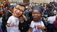 Pendukung Presiden baru Gustavo Petro, mengenakan topeng dirinya dan Wakil Presiden baru Francia Marquez. Terlihat seorang perempuan yang begitu antusias foto bersama topeng tersebut. (Ariana Cubillos/AP Photo)