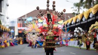 Gadis yang berjalan seperti model ini menggunakan kostum sate yang terihat lengkap dengan acar, bawang merah serta jeruk nipis.