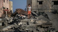 Seorang bocah berdiri di atas puing bangunan yang hancur usai gencatan senjata, Senin (8/8). Gencatan senjata yang ditengahi Mesir diharapkan dapat mengakhiri tiga hari konflik intens di Gaza.