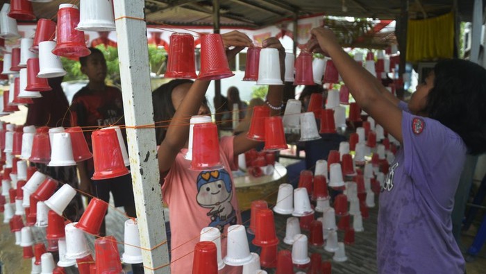 Warga membuat pernak pernik bertemakan merah putih menggunakan sampah plastik  di Perumahan Bumi Batara Mawang Permai, Kabupaten Gowa, Sulawesi Selatan, Minggu (7/8/2022). Pembuatan pernak pernik merah putih dengan memanfaatkan sampah plastik tersebut untuk mempercantik kompleks perumahan warga dalam rangka menyambut semarak HUT ke-77 Kemerdekaan Republik Indonesia. ANTARA FOTO/Abriawan Abhe/nym.