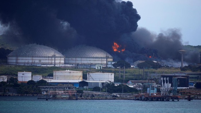 Api Masih Berkobar di Depot Minyak Kuba A lightning strikes through smoke from fuel storage tanks that exploded near Cuba's supertanker port in Matanzas, Cuba, August 8, 2022. REUTERS/Alexandre Meneghini