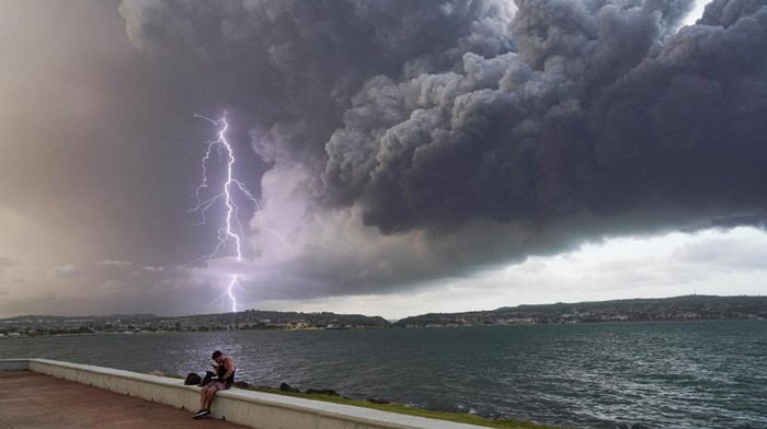 Api Masih Berkobar di Depot Minyak Kuba A lightning strikes through smoke from fuel storage tanks that exploded near Cuba's supertanker port in Matanzas, Cuba, August 8, 2022. REUTERS/Alexandre Meneghini
