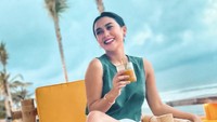Sepertinya pose dengan segelas minuman adalah gaya andalan Cita Citata. Ia tetap melakukannya saat tengah liburan di pinggir pantai.