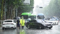 Petugas berjaga di ujung jalan dan mengalihkan arus lalu-lintas kendaraan. Hujan lebat mengguyur wilayah ibu kota Korea Selatan, mengubah jalan-jalan di distrik Gangnam menjadi layaknya sungai. (AP Photo/Ahn Young-joon)