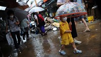 Seorang anak laki-laki menggunakan payung melewati jalan yang tergenang air setelah hujan deras di pasar tradisional di Seoul, Korea Selatan, Selasa (9/8/2022). (Kim Hong-Ji/Reuters)