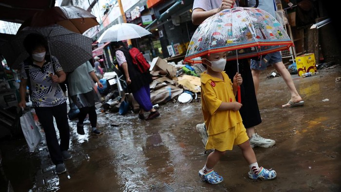 A boy using an umbrella makes his way through a road that was flooded after torrential rain at a traditional market in Seoul, South Korea, August 9, 2022.   REUTERS/Kim Hong-Ji