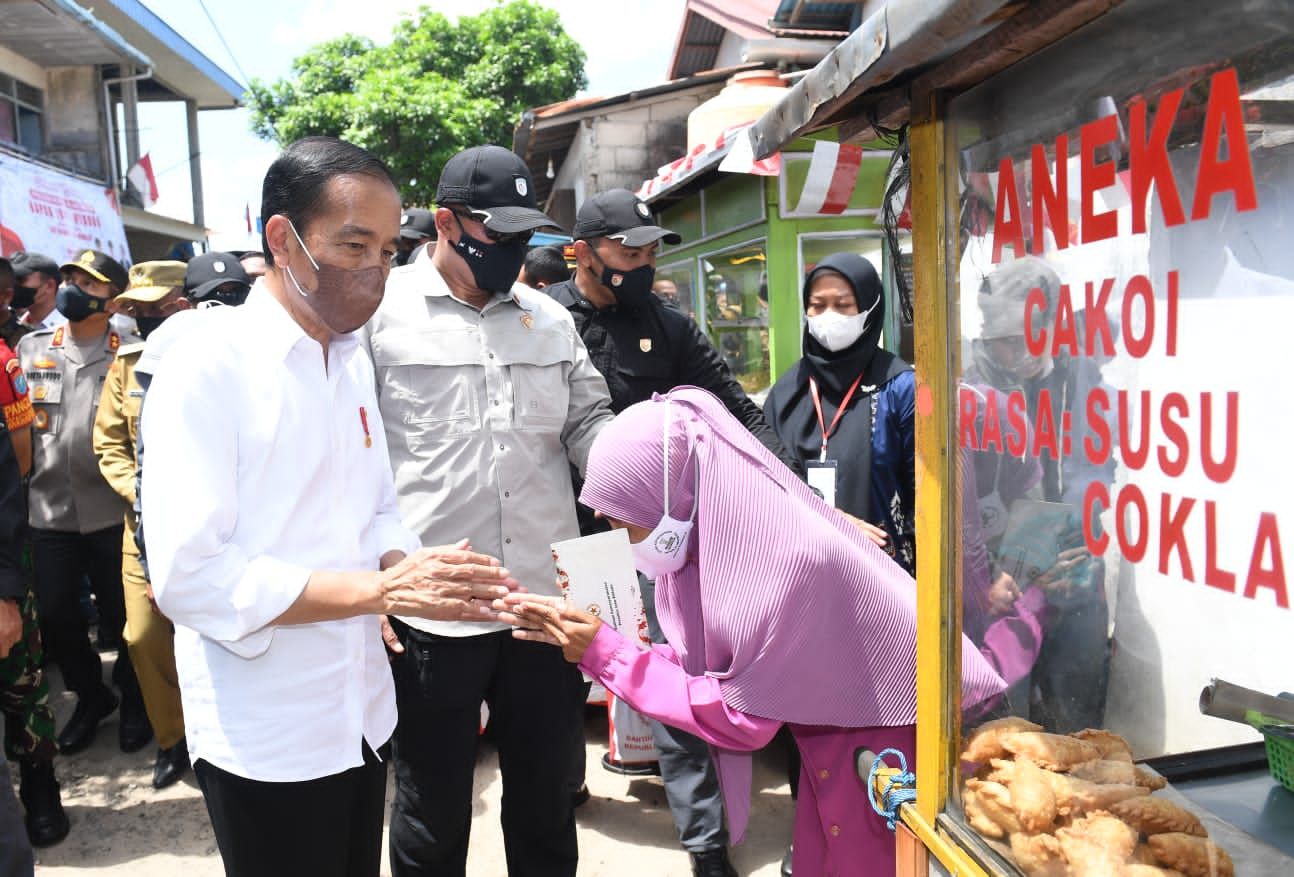Presiden Joko Widodo didampingi Ibu Iriana Joko Widodo menyerahkan Bantuan Modal Kerja (BMK) dan Bantuan Langsung Tunai (BLT) minyak goreng kepada peserta Program Keluarga Harapan (PKH) di Pasar Sungai Duri, Kabupaten Bengkayang, Provinsi Kalimantan Barat, pada Selasa, (9/8/2022). (Foto: Kris - Biro Pers Sekretariat Presiden)