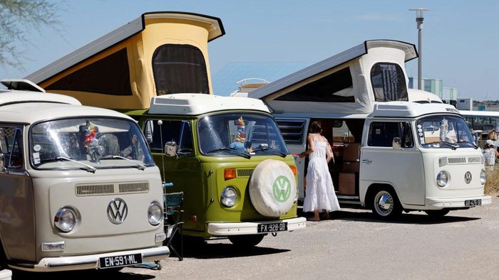 Pedestrians walk past vintage Volkswagen Kombi (VW Combi) vans during the third Fromentine Vintage Cup in Fromentine, western France, on August 7, 2022. - The Fromentine Cup is an annual gathering vintage van, Volkswagen Kombi trucks, and surfboarding enthusiasts, on the western coast of France. (Photo by Ludovic MARIN / AFP) (Photo by LUDOVIC MARIN/AFP via Getty Images)