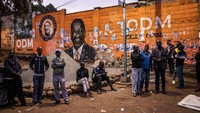 Sebagian warga menunggu malam pemilihan presiden di depan lukisan calon presiden koalisi Azimio La Umoja (Partai Koalisi Satu Kenya) Raila Odinga.