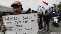Seorang peserta aksi membawa spanduk bertuliskan menjadi buruh bukan cita-cita kami tapi negara tanpa buruh bisa apa.