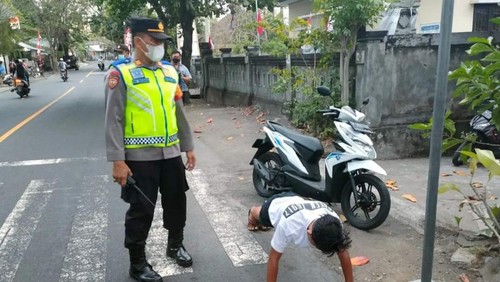 Salah satu pelanggar lalu lintas yang tidak mengenakan hel saat berkendara dikenakan sanksi push up di Kubu, Karangasem