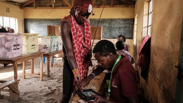Saat Suku Maasai Ikut Pilih Presiden Baru Kenya A leader of Maasai warrior puts his finger on the terminal of Kenya Integrated Electoral Management System (KIEMS) during Kenya's general election at the Masurura primary school polling station in Masurura on August 9, 2022. (Photo by Yasuyoshi CHIBA / AFP) (Photo by YASUYOSHI CHIBA/AFP via Getty Images)