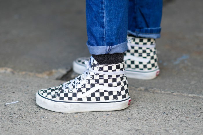 NEW YORK, NEW YORK - FEBRUARY 12: A guest wears blue denim rolled-up jeans pants, black socks, black and white checkered print pattern ankle Vans sneakers, outside Hardware LDN, during New York Fashion Week, on February 12, 2022 in New York City. (Photo by Edward Berthelot/Getty Images)