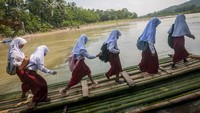 Siswa menaiki rakit bambu di Desa Haurgajrug, Lebak, Banten, Selasa (9/8/2022) untuk menyeberangi sungai Ciberang menuju sekolah. Putusnya akses jembatan gantung di desa tersebut mengakibatkan siswa terpaksa menyeberangi sungai setiap harinya menggunakan rakit dari bambu.