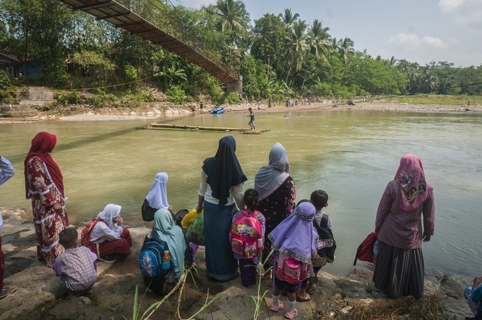 Siswa bersama orang tanya menunggu rakit bambu untuk menyeberangi sungai Ciberang di Desa Haurgajrug, Lebak, Banten, Selasa (9/8/2022). Putusnya akses jembatan gantung di desa tersebut mengakibatkan siswa terpaksa menyeberangi sungai setiap harinya menggunakan rakit dari bambu sehingga membahayakan keselamatan mereka. ANTARA FOTO/Muhammad Bagus Khoirunas/foc.