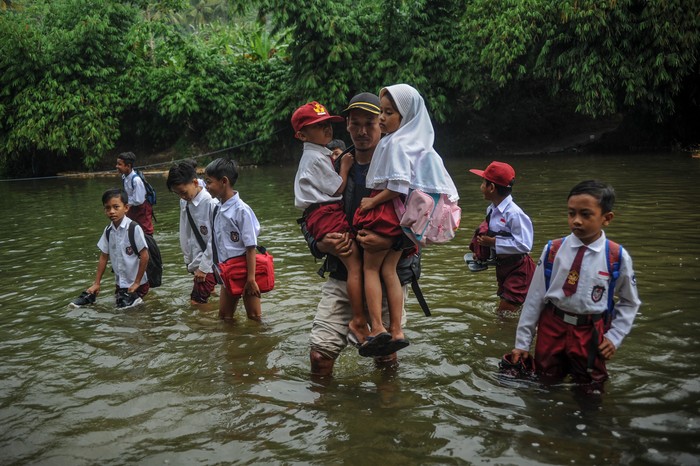 SISWA SEBERANGI SUNGAI UNTUK SEKOLAH Warga menggendong anaknya untuk menyeberangi Sungai Ciujung di Desa Sukaluyu, Cikadu, Cianjur Selatan, Kabupaten Cianjur, Jawa Barat, Rabu (10/8/2022). Sejak tahun 2018, ratusan siswa dari Desa Karyabakti terpaksa harus menerjang Sungai Ciujung untuk sekolah di SDN Padawaras Desa Sukaluyu karena tidak ada akses jalan lain untuk menuju sekolah mereka. ANTARA FOTO/Raisan Al Farisi/YU