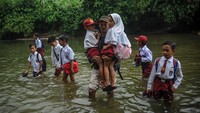 Warga membantu anak SD yang kesulitan menyeberang sungai. Satusan siswa dari Desa Karyabakti terpaksa harus menerjang Sungai Ciujung untuk sekolah di SDN Padawaras Desa Sukaluyu karena tidak ada akses jalan lain untuk menuju sekolah mereka.